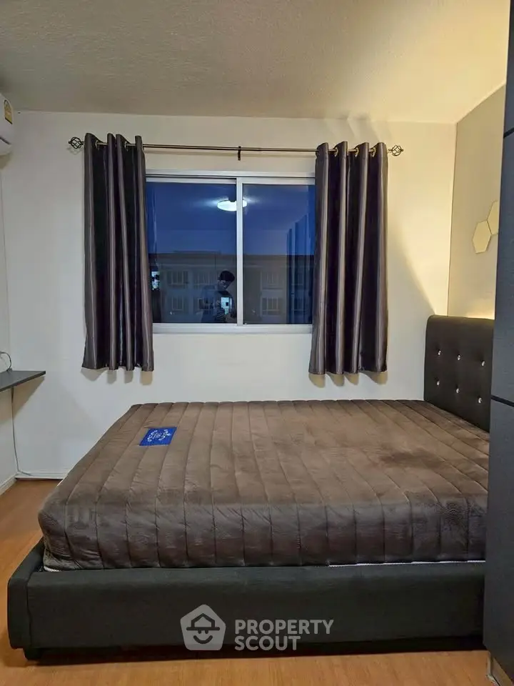 Cozy bedroom with modern decor and large window view.