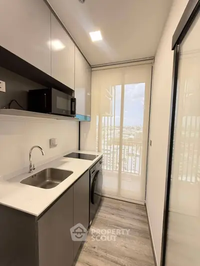 Modern kitchen with sleek cabinetry, integrated appliances, and a stunning city view from the window.
