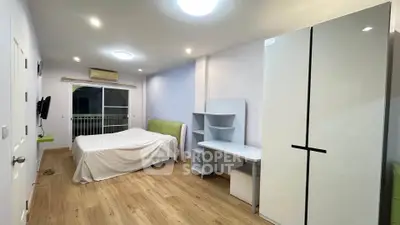 Spacious bedroom with modern furniture and wooden flooring, featuring a cozy bed and ample storage space.