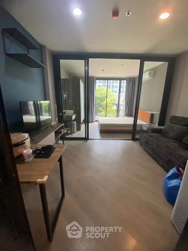 Modern studio apartment with open layout and large windows offering natural light and city views.
