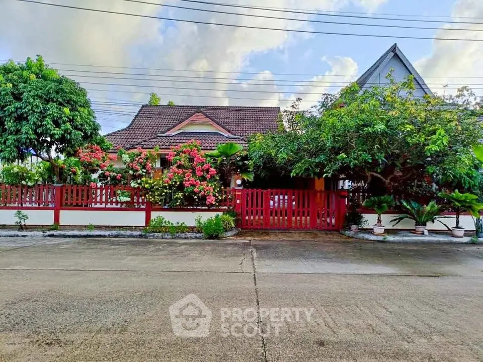 Charming suburban house with lush garden and red fence, perfect for family living.