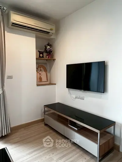 Modern living room with wall-mounted TV and air conditioning unit, featuring sleek wooden flooring and minimalist decor.
