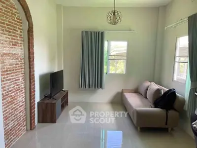Charming living room with modern decor and natural light, featuring a cozy sofa and sleek TV setup.