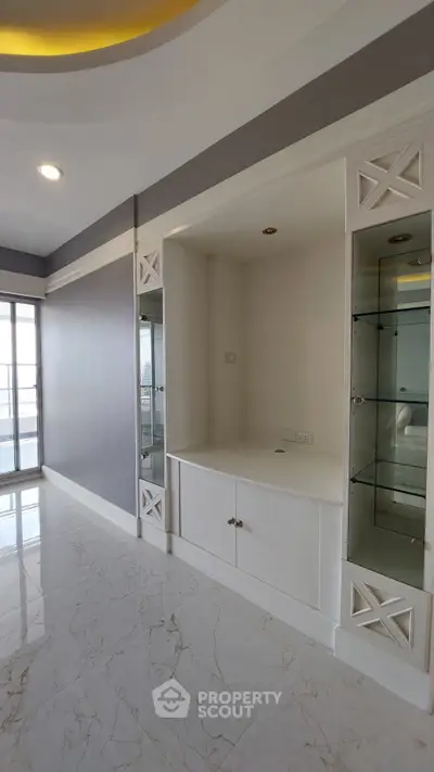 Spacious modern living room with elegant built-in shelves and marble flooring.