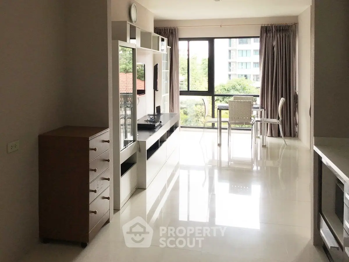 Bright modern living room with large windows and sleek furniture in a high-rise apartment.