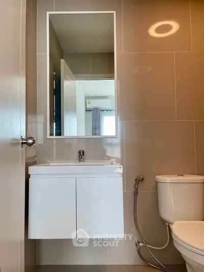 Modern bathroom with sleek fixtures and neutral tiles, featuring a wall-mounted sink and toilet.