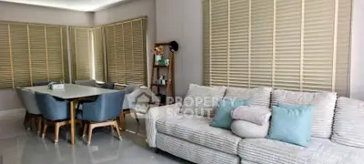 Spacious living room with modern furniture and large windows with blinds