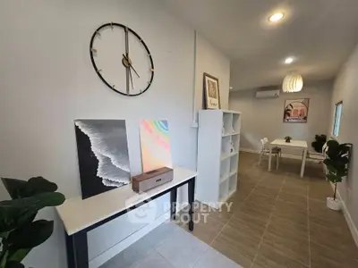 Modern interior with stylish decor, featuring a wall clock, artwork, and a dining area with contemporary furniture.
