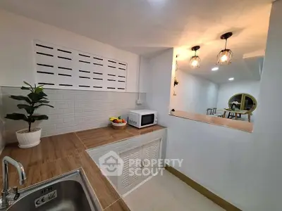 Charming kitchen with modern fixtures and open layout, featuring stylish lighting and wooden countertops.