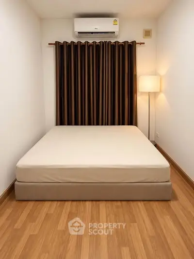 Cozy bedroom with wooden flooring, air conditioning, and elegant curtains.