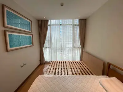 Spacious bedroom with large window and modern decor in a luxury apartment.