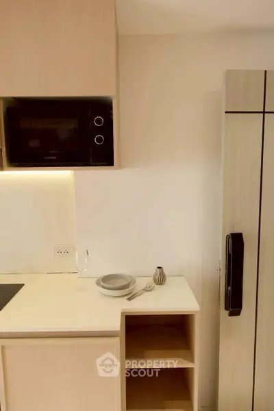 Modern kitchen with sleek appliances and minimalist design, featuring a built-in microwave and spacious fridge.