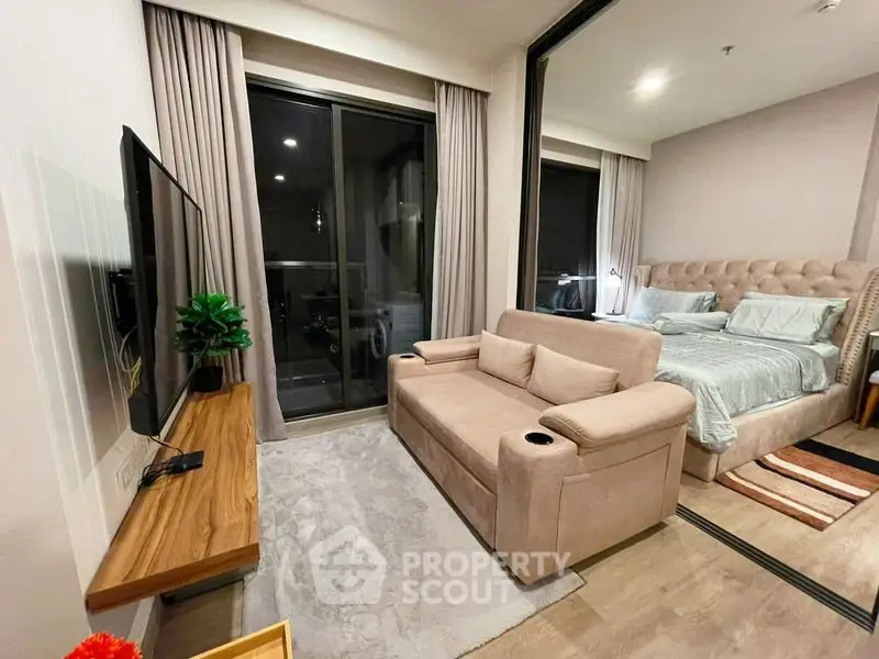 Modern studio apartment with cozy living area and stylish bedroom, featuring a sleek TV setup and elegant decor.