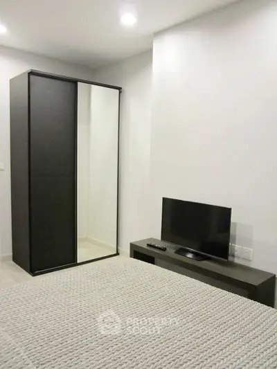 Modern bedroom with sleek wardrobe and flat-screen TV, perfect for minimalist living.