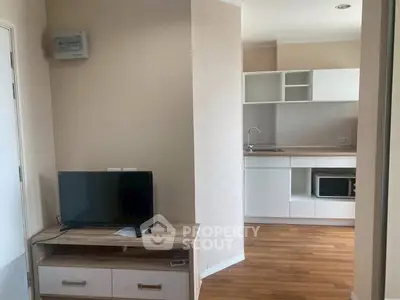 Modern apartment interior with compact kitchen and cozy living area featuring wooden flooring.