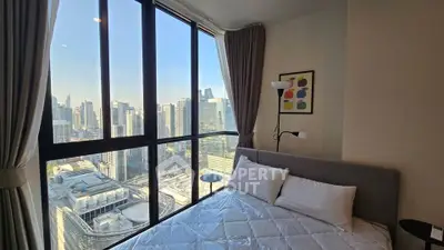 Modern bedroom with stunning city view through large windows, featuring cozy bed and stylish decor.