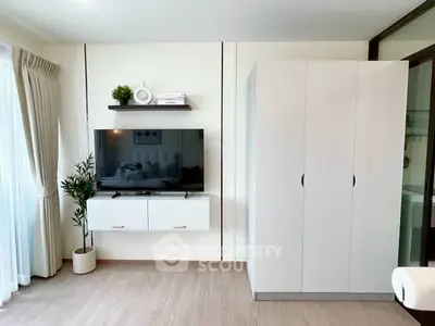 Modern living room with sleek TV setup and wardrobe, bright natural light