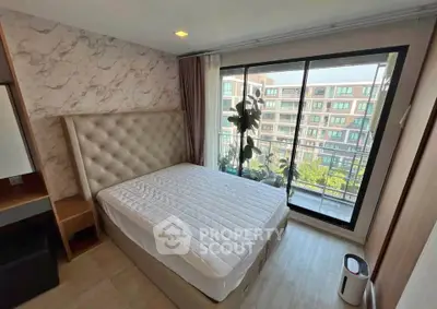 Modern bedroom with large window and city view, featuring elegant decor and natural light.