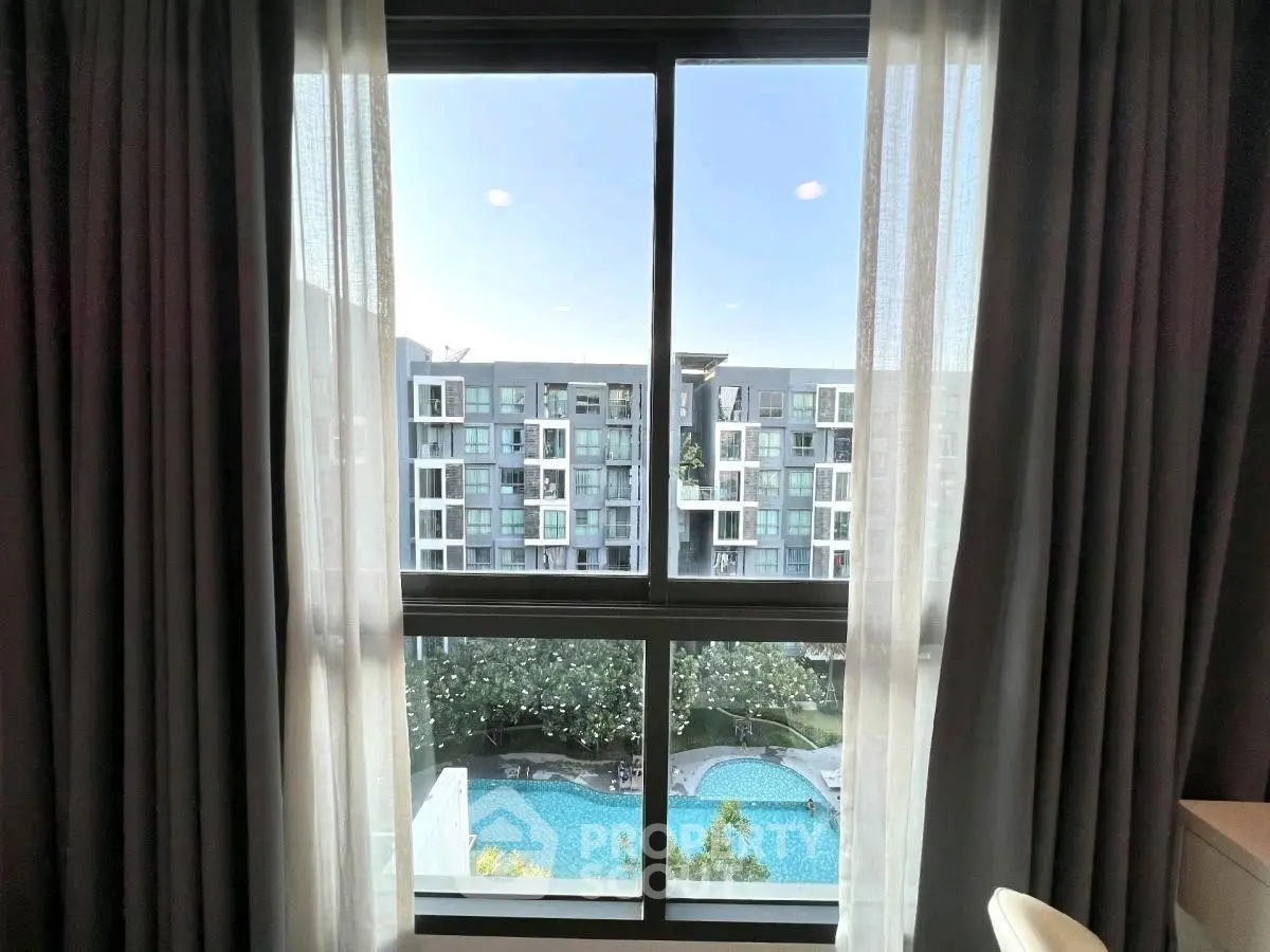 Stunning apartment view with pool and modern building through elegant window curtains.