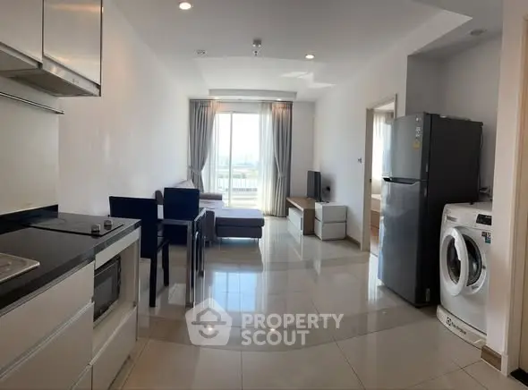 Modern open-plan living room with kitchen, featuring sleek appliances and a bright, airy atmosphere.