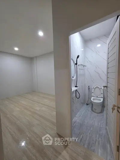 Modern bathroom with sleek design and adjacent empty room, perfect for customization.