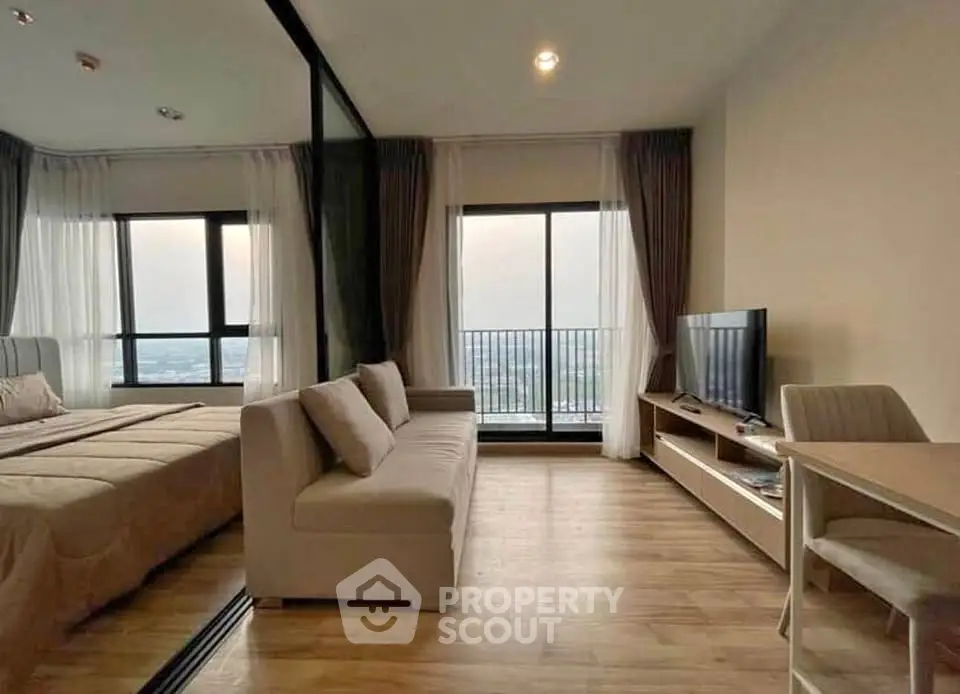 Modern studio apartment with large windows and stylish furnishings, offering a cozy and inviting living space.