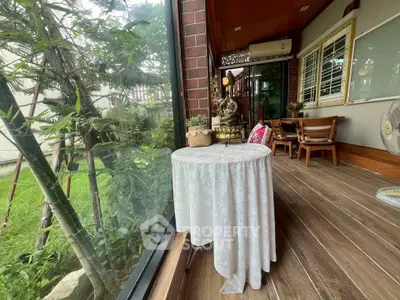 Charming garden view from a cozy balcony with wooden flooring and elegant decor.
