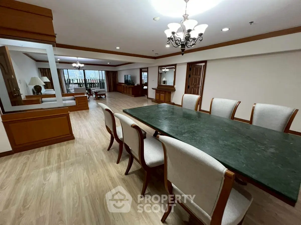Spacious dining area with elegant chandelier and large table in a luxurious apartment.