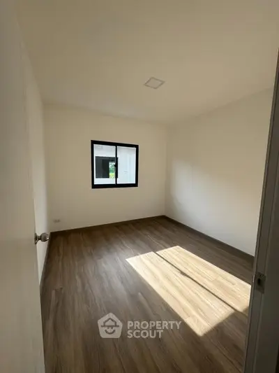 Spacious empty room with wooden flooring and natural light