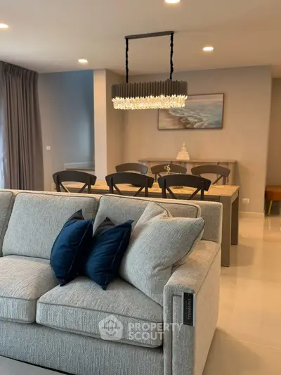 Elegant living room with modern chandelier and cozy dining area, perfect for stylish urban living.