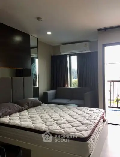 Modern bedroom with large window and balcony access in a stylish apartment.