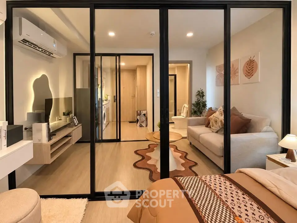 Modern apartment interior with stylish living room and cozy bedroom separated by glass partition.
