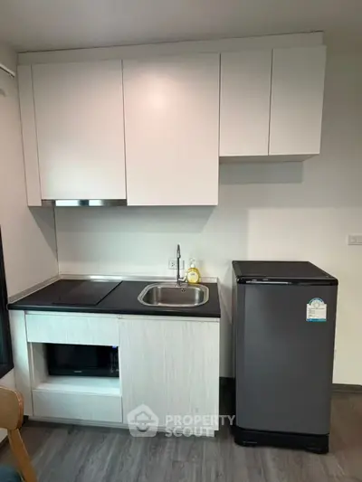 Modern compact kitchen with sleek cabinetry and mini fridge, perfect for urban living.