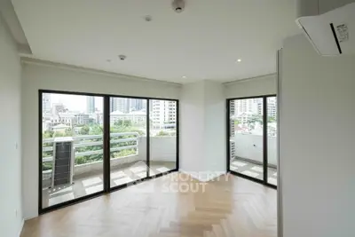 Spacious corner unit with large windows and city view, featuring elegant herringbone flooring.