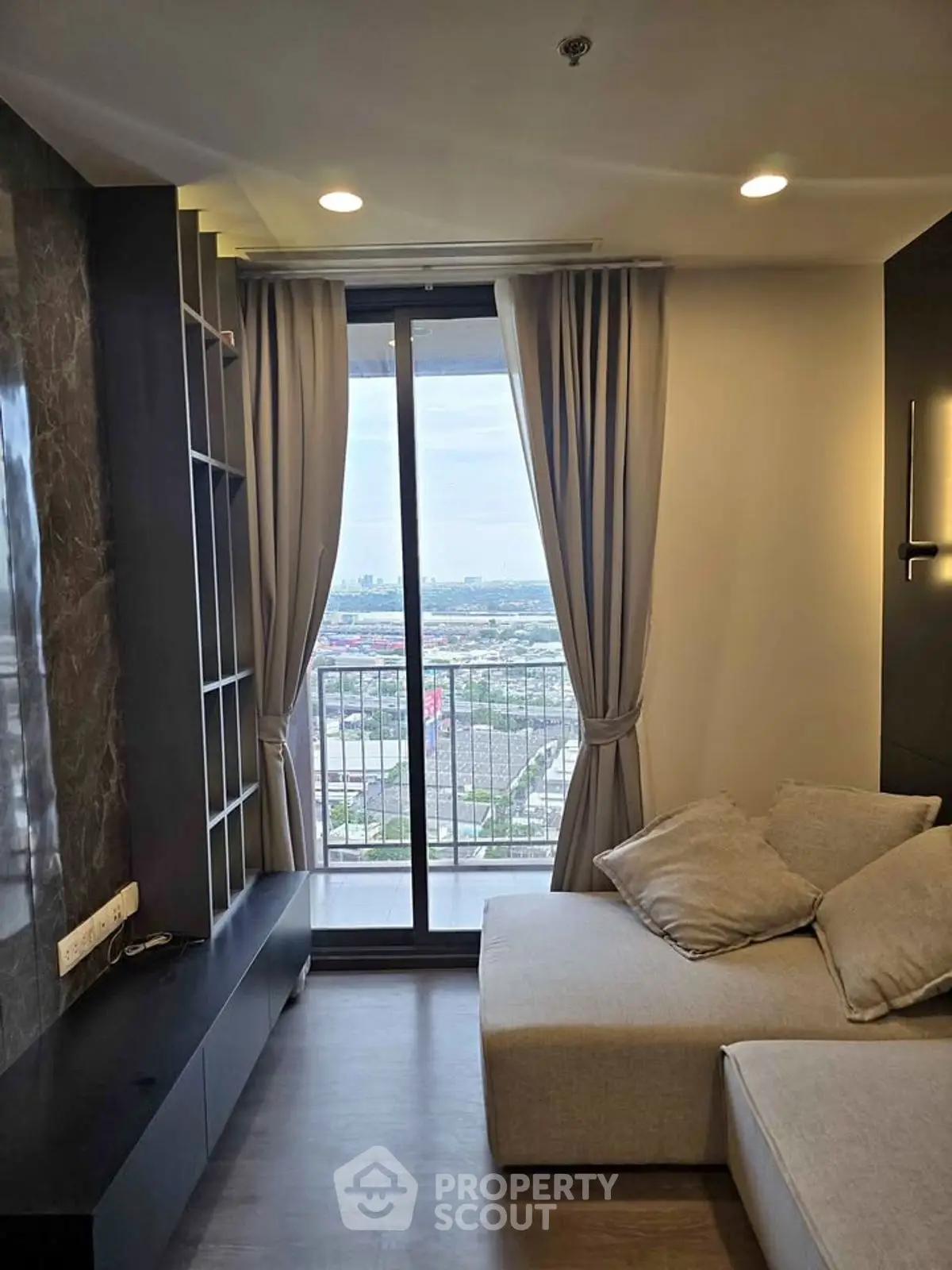 Modern living room with large window and balcony offering stunning city view