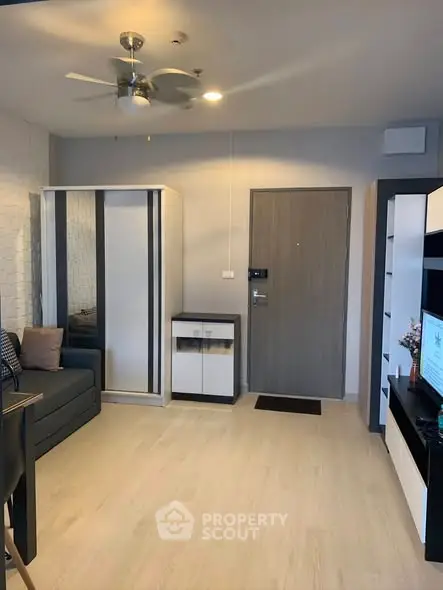 Modern living room with sleek furniture and neutral tones, featuring a ceiling fan and stylish decor.