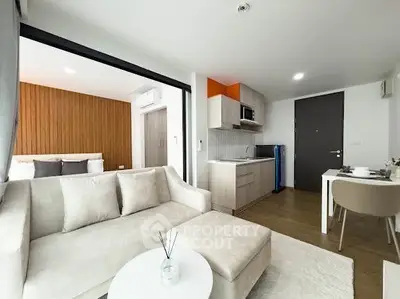 Modern open-plan living room with cozy sofa and compact kitchen in stylish apartment.