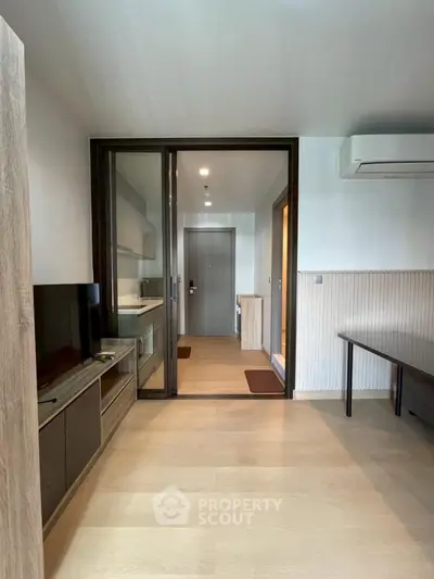 Modern living room with sleek design and air conditioning, featuring a glass partition and wooden flooring.