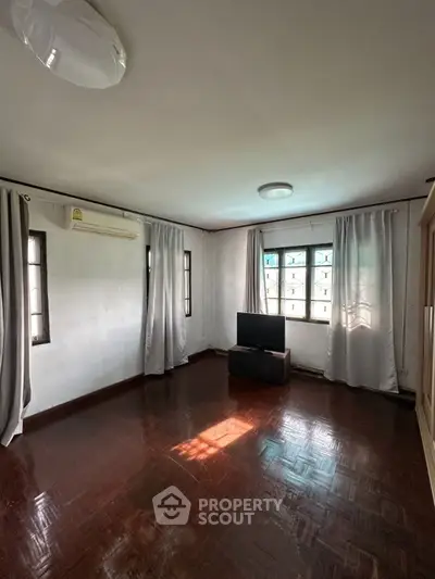 Spacious living room with natural light and wooden flooring, ideal for cozy gatherings.