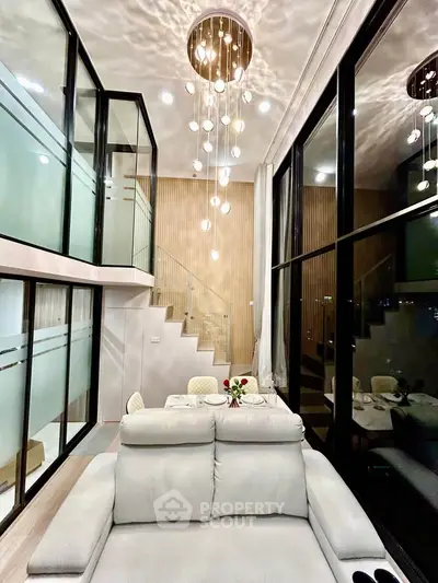 Luxurious modern living room with high ceilings and elegant chandelier in a stylish duplex apartment.