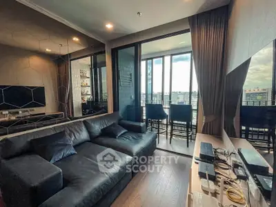 Modern living room with sleek black sofa and city view balcony, perfect for urban living.