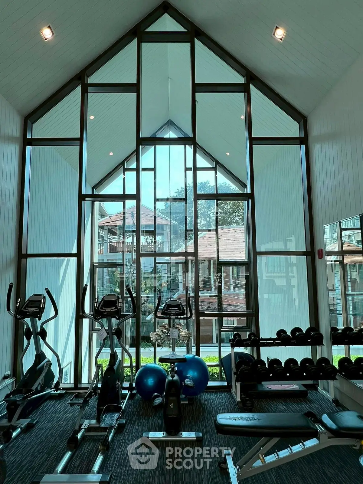 Spacious gym with modern equipment and large windows offering scenic views in a luxury residential complex.