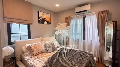 Cozy bedroom with stylish decor and natural light, featuring elegant curtains and modern air conditioning.
