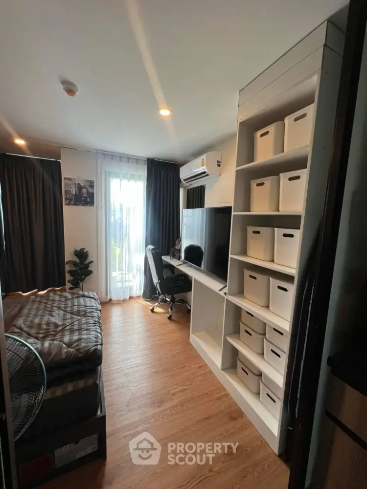 Modern bedroom with workspace, featuring sleek desk, chair, and organized shelving in cozy apartment.