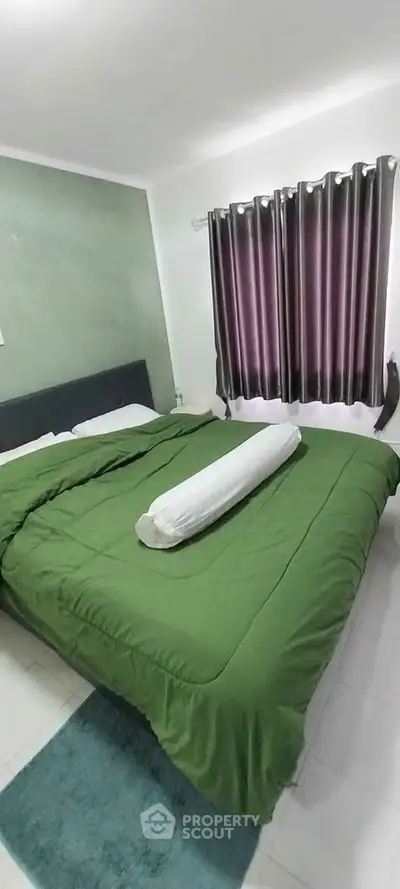 Cozy bedroom with green bedding and purple curtains, perfect for relaxation.