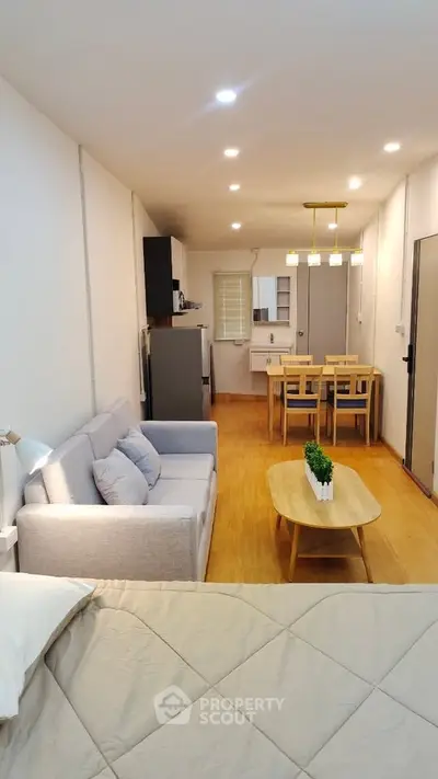 Modern open-layout living room with cozy sofa and dining area in a stylish apartment.