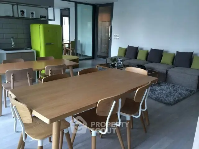 Modern open-plan living and dining area with stylish furniture and vibrant green fridge.