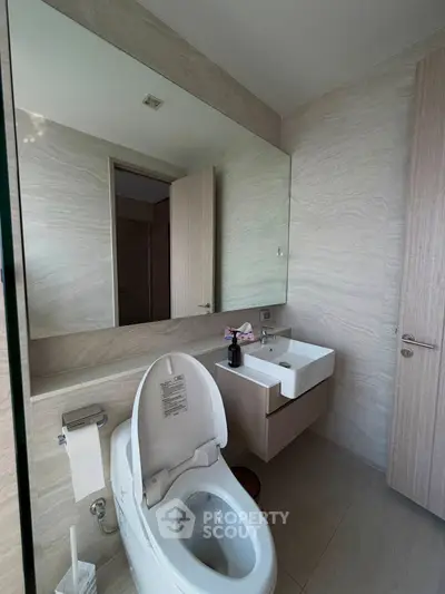 Modern bathroom with sleek fixtures and large mirror in contemporary apartment.