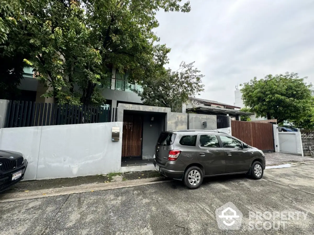 Modern residential property with gated entrance and parked car in suburban neighborhood.