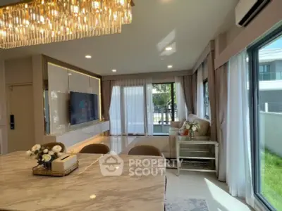 Luxurious living room with elegant chandelier and marble dining table, featuring large windows and modern decor.